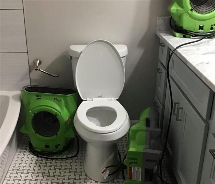same bathroom with SERVPRO equipment around toilet 