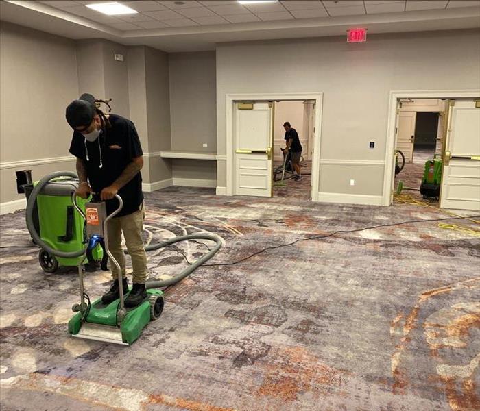 Two male employees cleaning carpet in hotel ballroom
