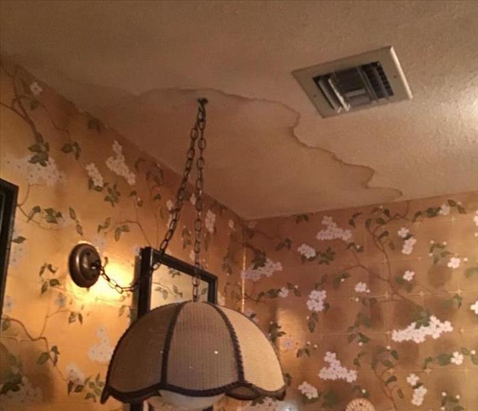 dining room with floral wallpaper and water damage stain above hanging light