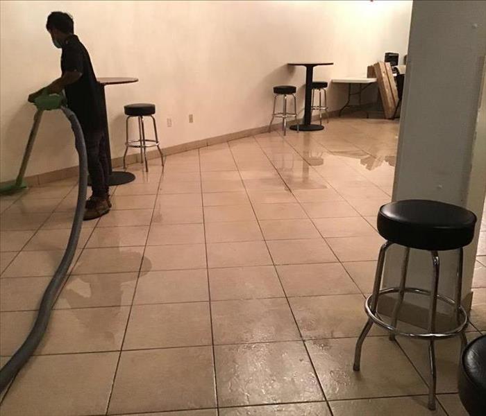 Man cleaning up standing water on tile floor