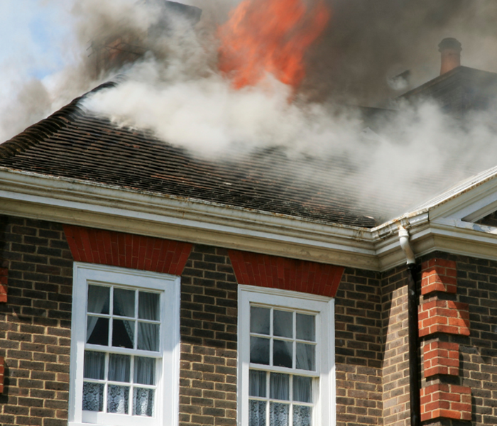 Brick house with fire and smoke coming through roof