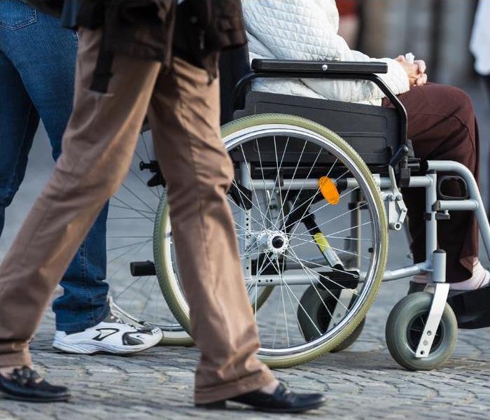 person in wheelchair surrounded by people walking